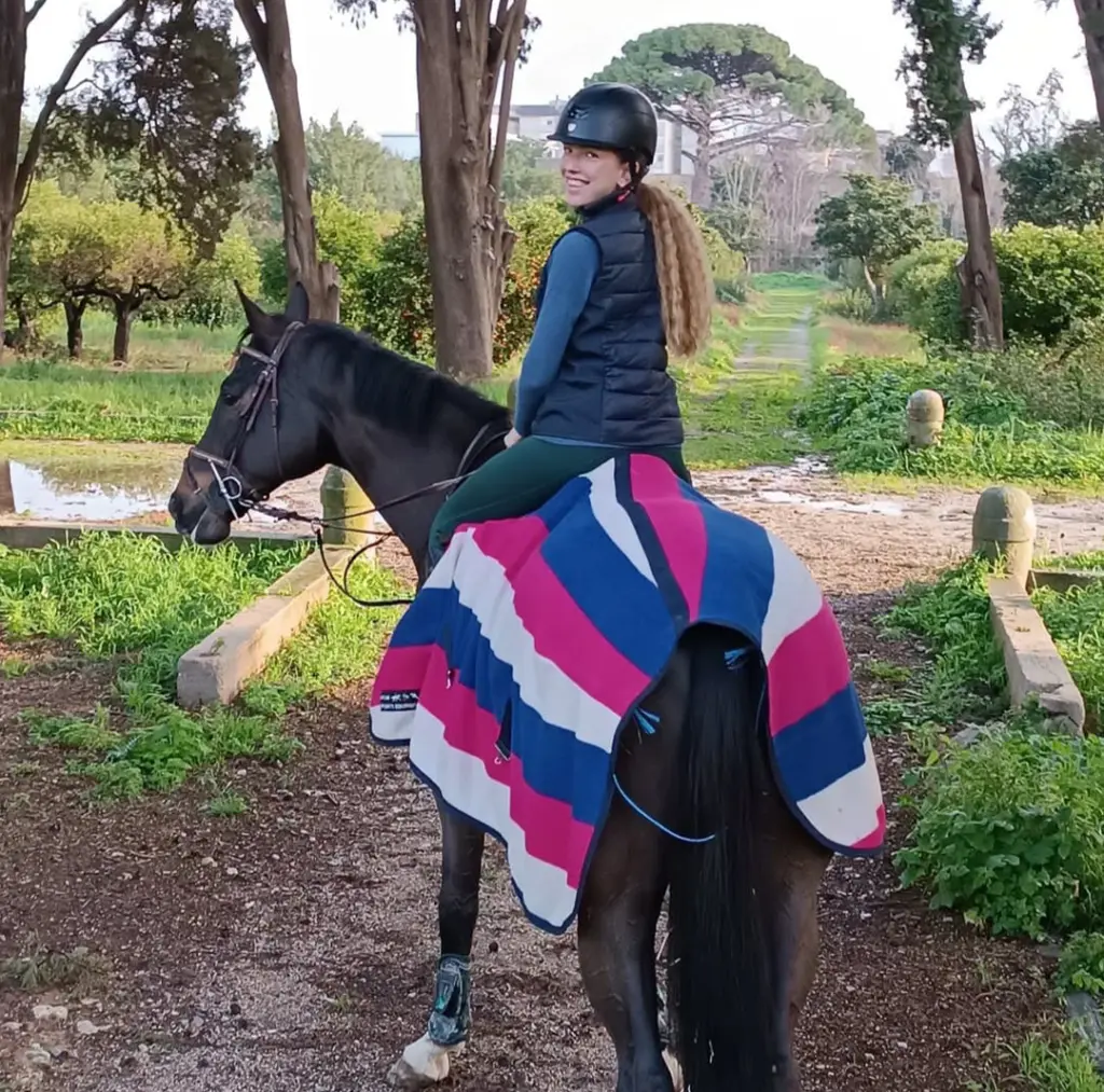 Allieva del C.I.S. a cavallo lungo un sentiero immerso nel verde.