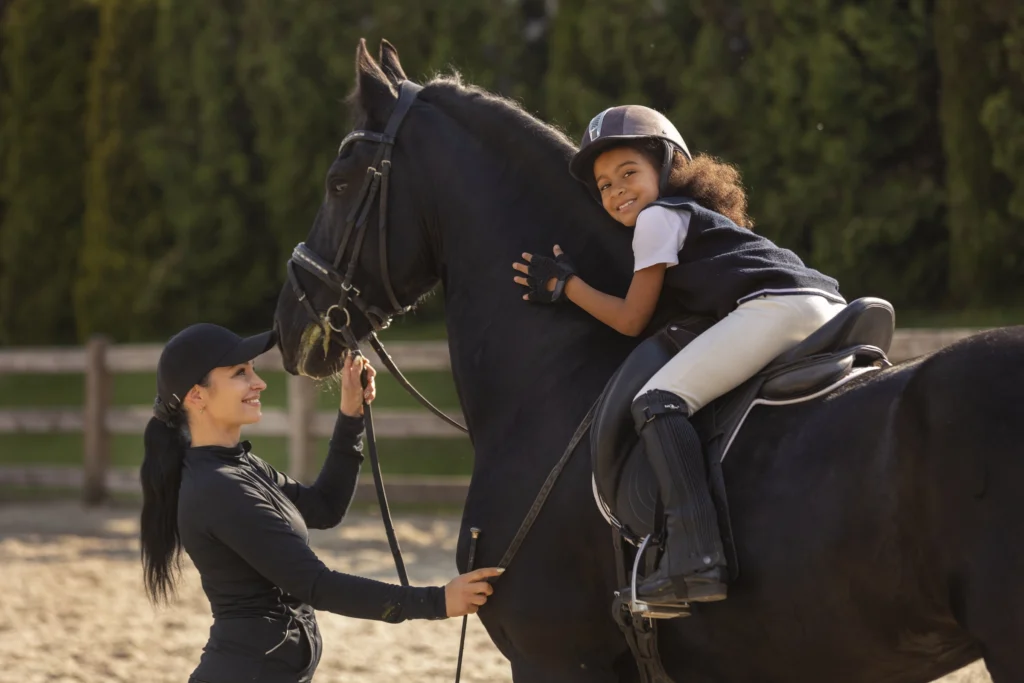 Bambina a cavallo durante una lezione di equitazione, primo approccio sicuro allo sport equestre